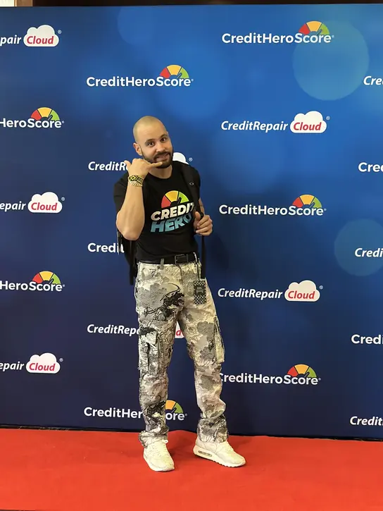 Darian Avello in front of a CreditRepair Cloud and CreditHeroScore event backdrop